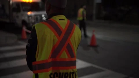 Security guard holding stop slow down sign at night construction site in Canada Stock Footage 247925069