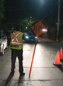 Security guard holding stop/slow down sign at night construction site in Toronto Stockfoto's