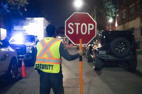Security guard holding stop/slow down sign at night construction site in Toronto Stockfoto's