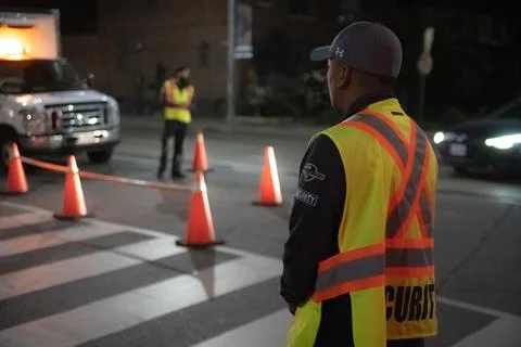 Security guard holding stop/slow down sign at night construction site in Toronto Stockfoto's