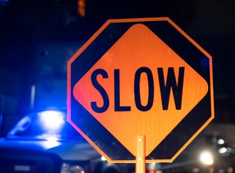 Security guard holding stop/slow down sign at night construction site in Toronto Stock Photos