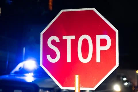 Security guard holding stop/slow down sign at night construction site in Toronto Stock Photos