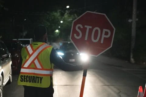 Security guard holding stop/slow down sign at night construction site in Toronto Stockfoto's