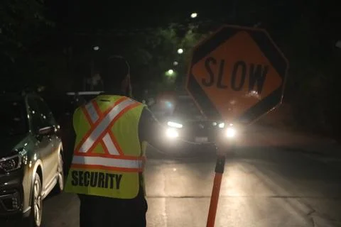 Security guard holding stop/slow down sign at night construction site in Toronto Stock Photos