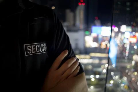 Security guard looking down cityfull of lights at night.. Stock Photos