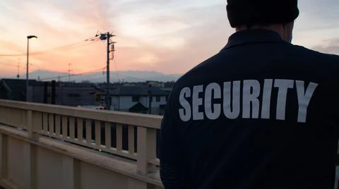 Security guard looking down street and sunset Stock Photos