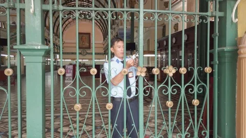Security guard man unlocks the gate of Post Office (Buu Dien), Saigon. Stock Footage 115066467
