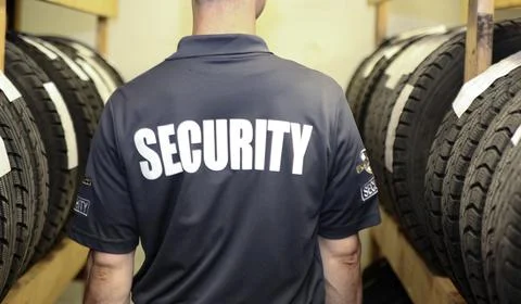 Security guard patrolling inside warehouse of tires. Stock Photos
