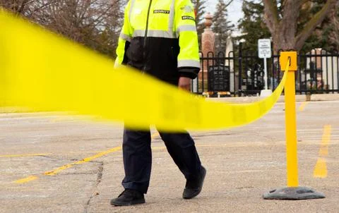 Security guard setting up a caution tape to do parking enforcement at guest park Stockfoto's