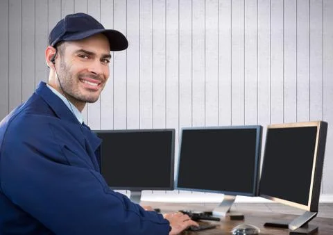 Security guard smiling in front of the computers with white wood background Stock Photos