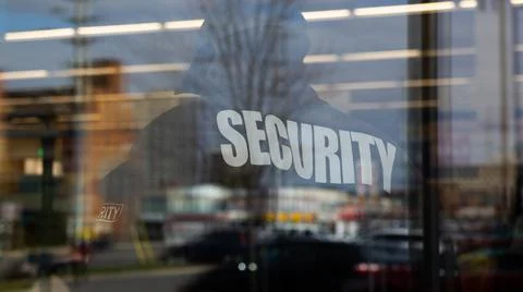 Security guard standing inside commercial building nearby the window reflecti Stock Photos