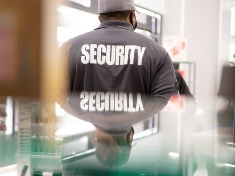 Security guard standing inside commercial building nearby the window reflecti Stock Photos