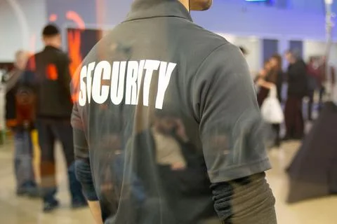 Security guard standing inside commercial building nearby the window reflecti Stock Photos