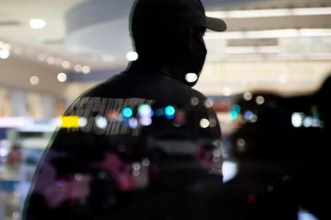 Security guard standing inside commercial building nearby the window reflecti Stock Photos
