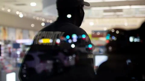Security guard standing inside commercial building nearby the window reflecti Stock Photos