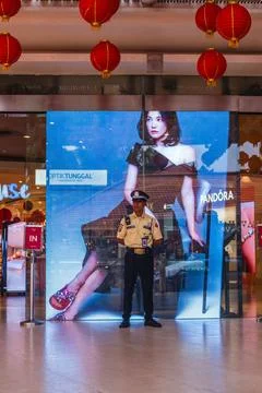 Security Guard Standing Before Large Digital Retail Advertisement Stock Photos