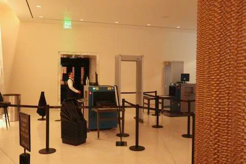 Security guard standing next to scanning machines at a checkpoint Stock Photos