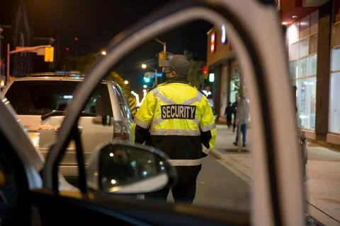 Security guard standing by next to security car at night city Stock Photos