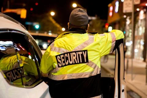 Security guard standing by next to security car at night city Stock Photos