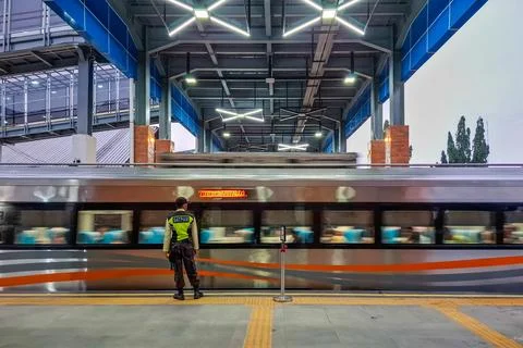 The security guard stands beside the platform as the train rumbles past. Foto stock
