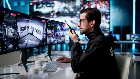 Security Guard Talks On Radio While Watching Cameras Stock Footage 334536640