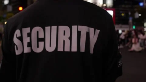 Security guard walking through street of big city at night Stock Footage 153888610