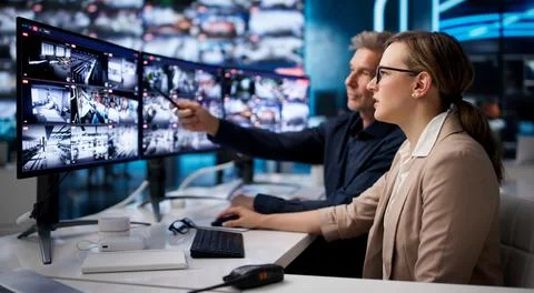Security Guard Watches Multiple CCTV Screens To Monitor Building Security. Stock Photos