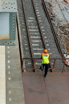 Security guard wearing a high visibility vest is standing near the railways Stock Photos