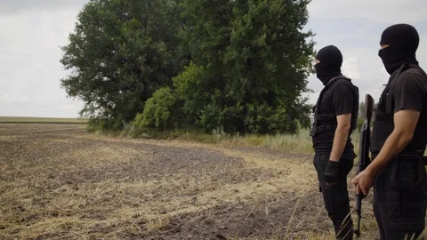 Security guards in full equipment, gun, body armor, masks inspect the territory Stock Footage 95204678