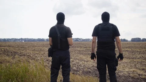 Security guards in full equipment, gun, body armor, masks inspect the territory Stock Footage