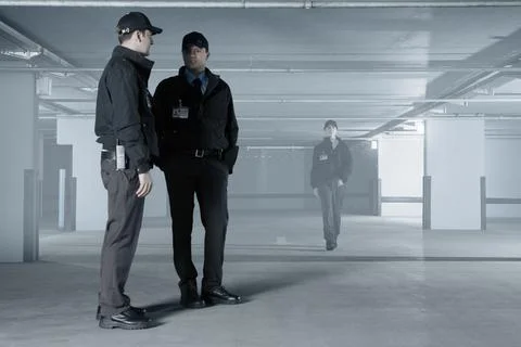 Security guards talking in empty parking garage Stock Photos