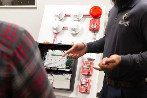 Security guards training how to use fire alarm and mock sprinkler system Stockfoto's