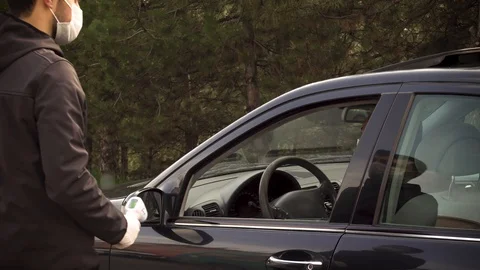 Security guy measures a driver's body temperature and allows him to continue Stock Footage 128558152