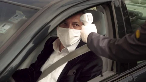 Security guy measures a healthy driver's body temperature with thermometer Stock Footage 128558095