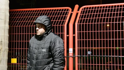 Security man at cold night. man in the hood warms up on the bench at night. Video stock 104874664