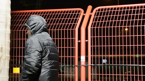 Security man at cold night. man in the hood warms up on the bench at night. Видео 104874768