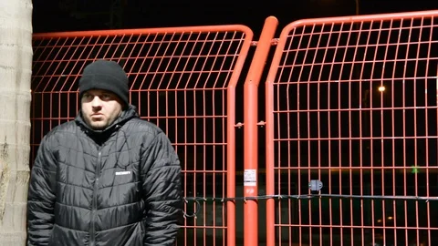 Security man at cold night. man in the hood warms up on the bench at night. Vídeos de archivo 104875000