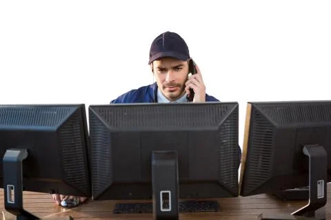 Security officer talking on phone while using computer Stock Photos