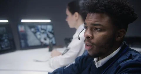 Security operator talks with colleague and types keyboard Foto stock