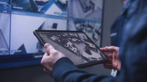 Security operator zoom CCTV cameras using tablet Stock Footage 240479581
