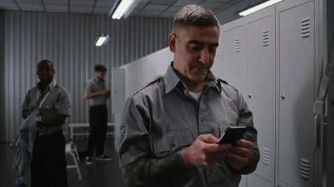 Security Personnel Viewing Smartphone Notifications at Locker in Staff Changing Stock Footage 334012295