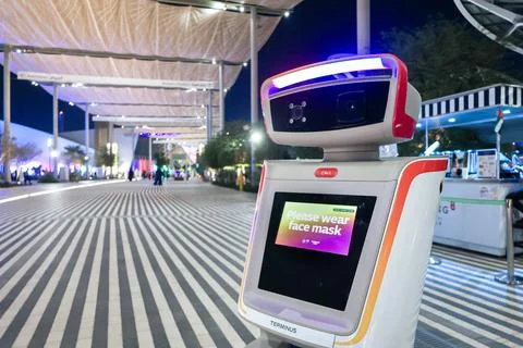 Security robot keeping order at exhibition. Machine ask to wear on face mask in Stock Photos