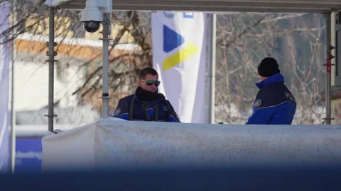 Security staff beside snow-covered barriers during the World Economic Forum Stock Footage 345299461