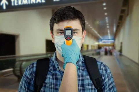 Security staff checking the temperature of an airport passenger 库存照片