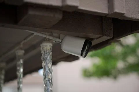 Security surveillance camera under residential house roof close up Stock Photos