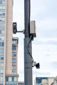 Security surveillance cameras installed on a grey metal pole against city Stock Photos