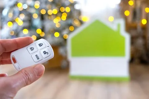 Security System Keychain in hand on background fairy lights Christmas tree .. Foto stock