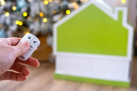 Security System Keychain in hand on background fairy lights Christmas tree .. Stock Photos