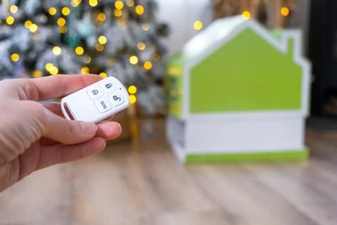 Security System Keychain in hand on background fairy lights Christmas tree .. Stock Photos
