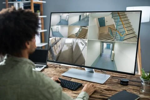 Security System Operator Looking At CCTV Footage At Desk Foto stock